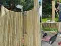 Bygga utedusch: en man monterar en träkonstruktion med duschmunstycke och slangar i en trädgård.