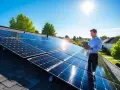 Man på tak med solceller kollar på surfplatta. Undrar du vad kostar 50 kvm solceller?