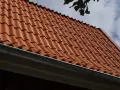 Rött tegeltak med rännsten. Taket har en minimal taklutning för betongpannor, vilket ger ett stilrent utseende.