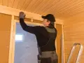 Man bygger bastu inomhus, monterar träpanel i taket.