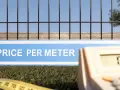 Grönt gräs, ett staket och en kalkylator. Skylten visar "PRICE PER METER", vilket indikerar staket pris per meter.