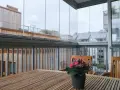 Träbord och stolar på en inglasad balkong med utsikt över stadens tak. Tänk på inglasad balkong pris för din egen dröm.