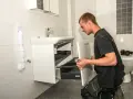 Hantverkare installerar ett nytt badrumsskåp under en totalrenovering av badrum.