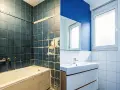 Före- och efterbild på ett badrum. Det gamla, mörka badrummet har renoverats till ett ljust och modernt, handikappanpassat badrum med blå väggar och vitt kakel.