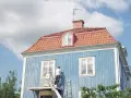 Man målar om en blå träfasad från en lift. En dropplist fasad skyddar mot regn.