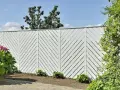Vitt staket med diagonalt mönster ger staket inspiration. Vackert mot blå himmel och grönska.