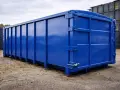 En stor, blank blå container står på grus. Den är redo att måla och förberedd för transport.
