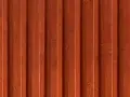 Detaljbild av en rödbrun, gammaldags lockpanel i trä. Panelen har vertikala spår och ger en känsla av traditionellt svenskt byggnadssätt.