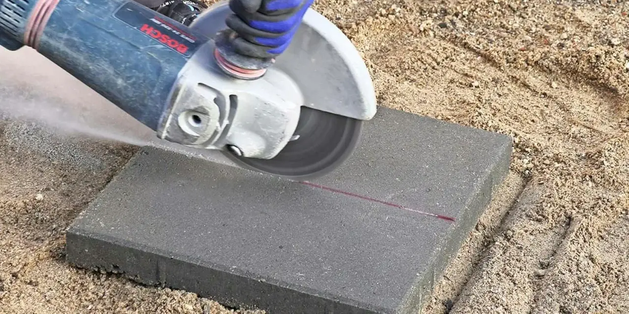 Vinkelslip används för att kapa betongplattor på en sandig yta.