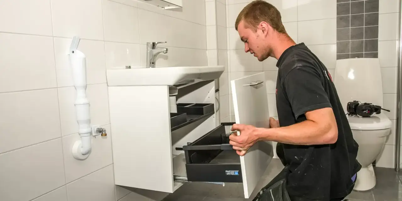 Hantverkare installerar ett nytt badrumsskåp under en totalrenovering av badrum.