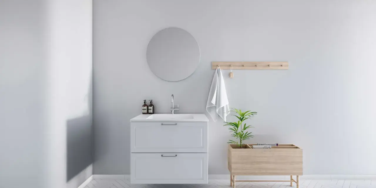 Minimalistiskt badrum med vitt kommod, rund spegel och trädetaljer. En bra utgångspunkt för att fundera på vad kostar det att renovera ett litet badrum.