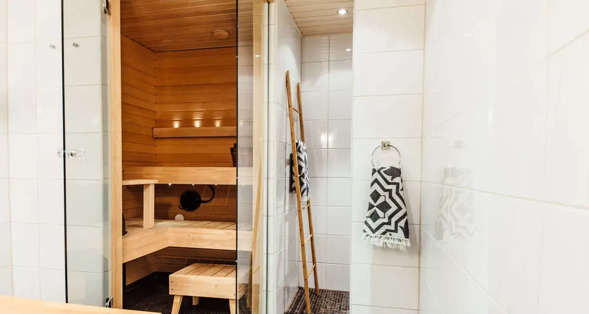 En liten bastu i badrummet, perfekt för avkoppling. Trädetaljer och en duschhörna skapar en spa-känsla.