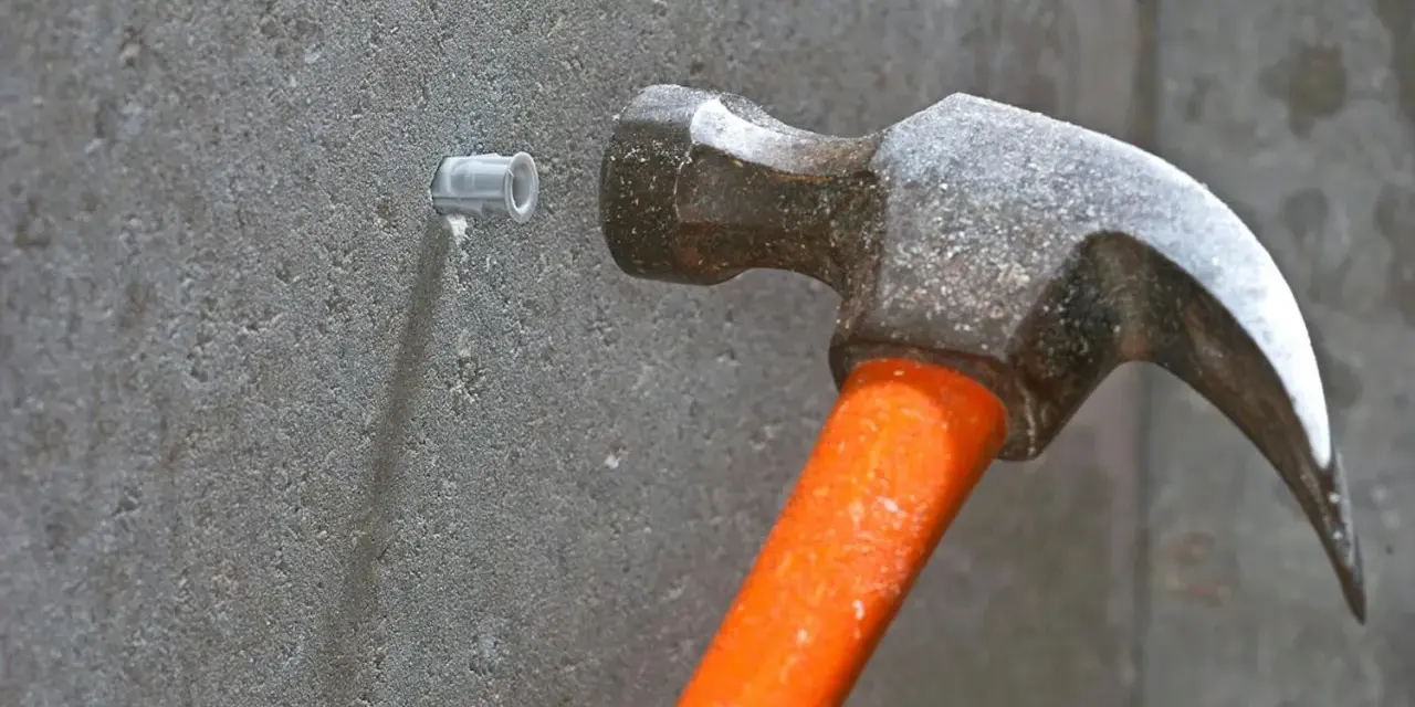 Hammare slår in en plugg i betongvägg. Förberedelse för att skruva i betong.