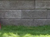 Två staplar takpannor, en svart och en röd, lutar mot en mur av grå betongblock. Undrar vad kostar takpannor?