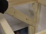 En person håller på att såga snett en träbit som ska bli en del av en konstruktion.