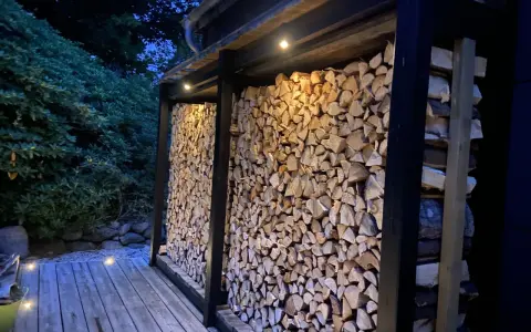 En vedbod är färdig att bygga, fylld med ved och belyst av små lampor.
