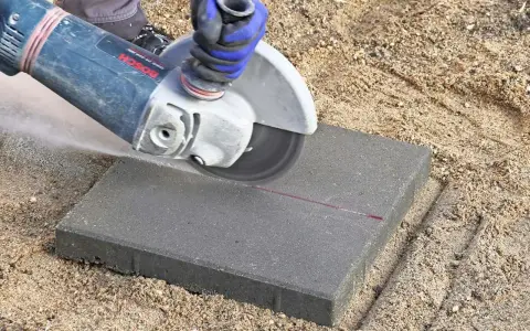 Vinkelslip används för att kapa betongplattor på en sandig yta.