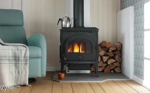 Mysig brasa i gjutjärnskamin med ved och tekopp. Tänk på renovera skorsten pris för en säker och effektiv värme.