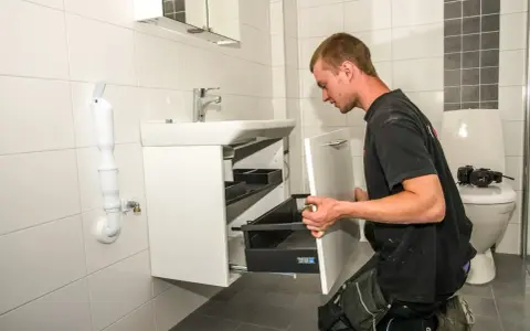 Hantverkare installerar ett nytt badrumsskåp under en totalrenovering av badrum.