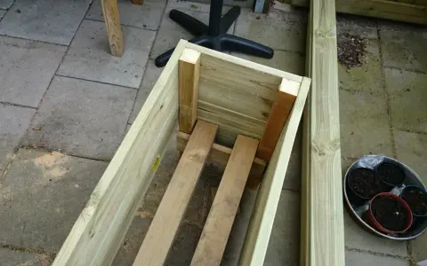 Påbörjat projekt att bygga blomlåda av tryckimpregnerat virke. Några krukor med jord står redo.