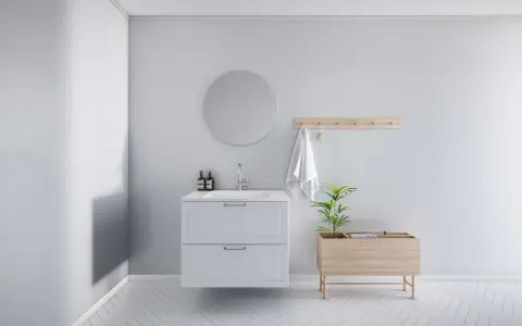 Minimalistiskt badrum med vitt kommod, rund spegel och trädetaljer. En bra utgångspunkt för att fundera på vad kostar det att renovera ett litet badrum.