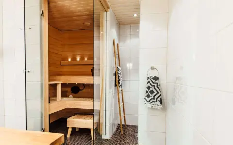 En liten bastu i badrummet, perfekt för avkoppling. Trädetaljer och en duschhörna skapar en spa-känsla.