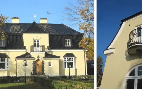 Gult hus med spritputsad fasad, svart tak, balkong och vackra fönster.