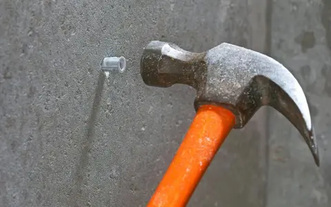 Hammare slår in en plugg i betongvägg. Förberedelse för att skruva i betong.