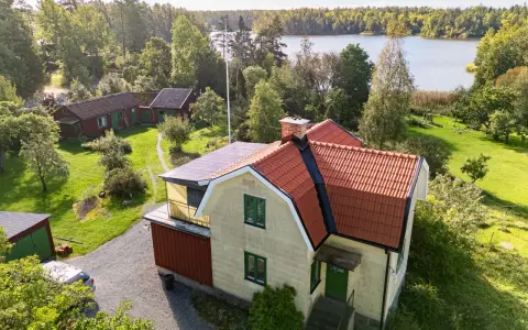 Gult hus med tegeltak vid en sjö. En takrenovering kostnad kan vara en bra investering för att skydda huset.