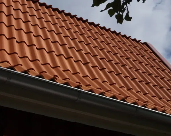 Rött tegeltak med rännsten. Taket har en minimal taklutning för betongpannor, vilket ger ett stilrent utseende.