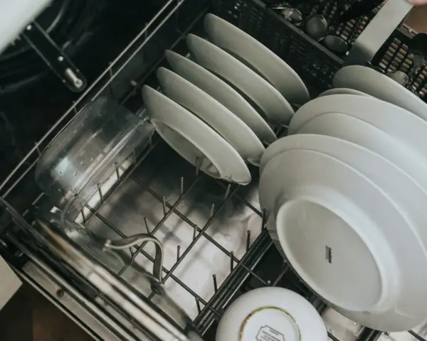 Tallrikar och en plastbehållare redo för diskmaskinen. En ny diskmaskin gör det enklare att installera diskmaskin.
