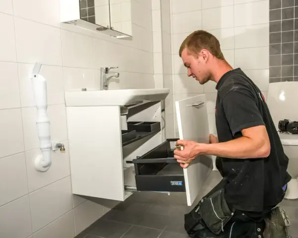 Hantverkare installerar ett nytt badrumsskåp under en totalrenovering av badrum.