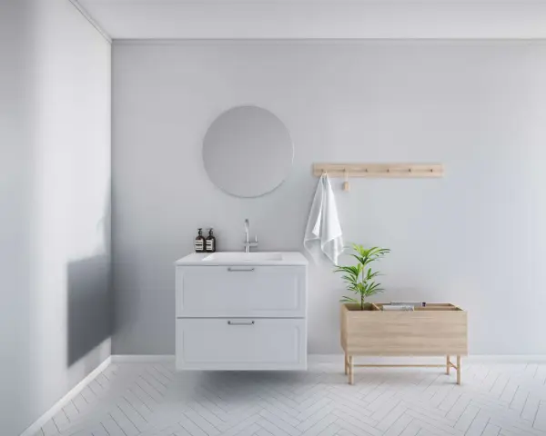 Minimalistiskt badrum med vitt kommod, rund spegel och trädetaljer. En bra utgångspunkt för att fundera på vad kostar det att renovera ett litet badrum.