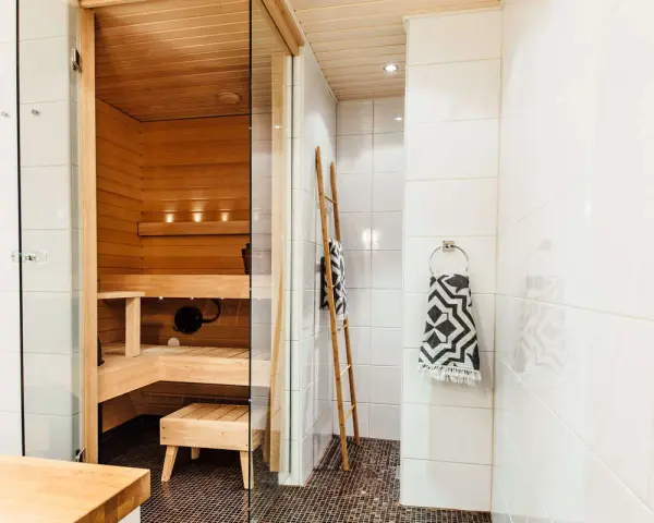 En liten bastu i badrummet, perfekt för avkoppling. Trädetaljer och en duschhörna skapar en spa-känsla.