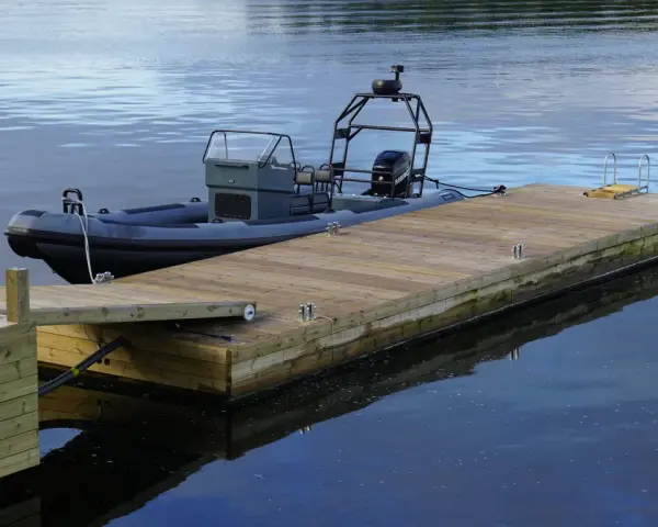 En grå RIB-båt ligger förtöjd vid en nybyggd flytbrygga. Perfekt för att bygga flytbrygga och njuta av vattnet.