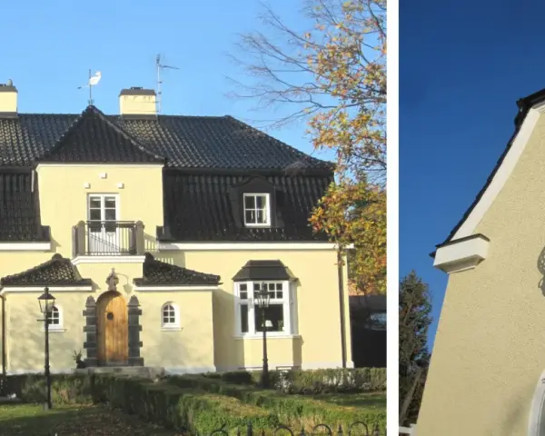 Gult hus med spritputsad fasad, svart tak, balkong och vackra fönster.