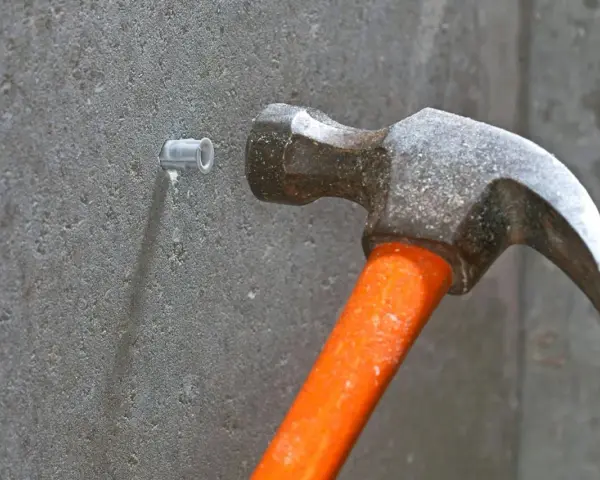 Hammare slår in en plugg i betongvägg. Förberedelse för att skruva i betong.