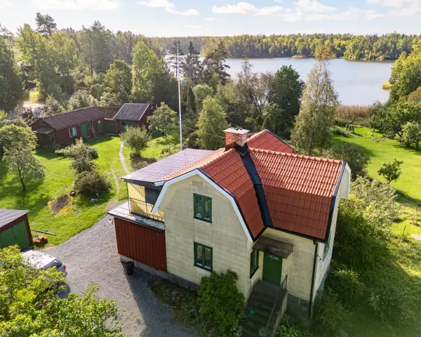 Gult hus med tegeltak vid en sjö. En takrenovering kostnad kan vara en bra investering för att skydda huset.
