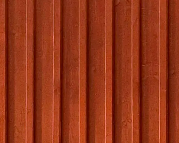 Detaljbild av en rödbrun, gammaldags lockpanel i trä. Panelen har vertikala spår och ger en känsla av traditionellt svenskt byggnadssätt.