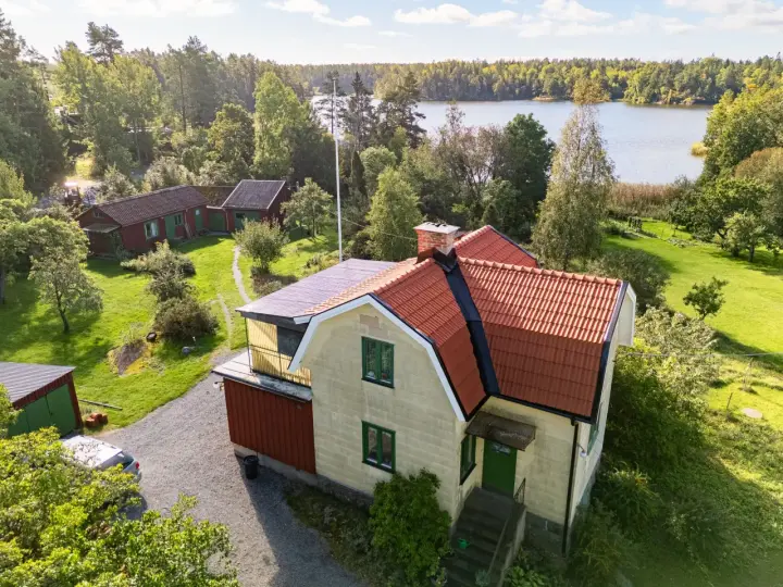 Gult hus med tegeltak vid en sjö. En takrenovering kostnad kan vara en bra investering för att skydda huset.