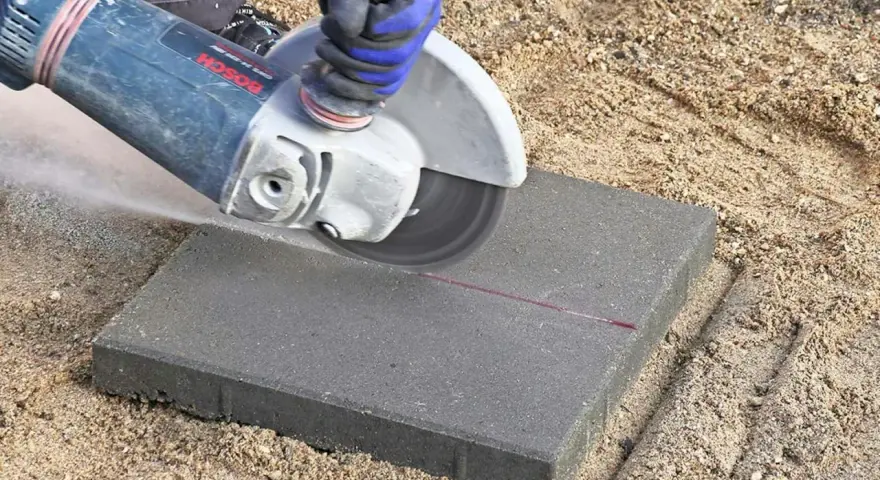Vinkelslip används för att kapa betongplattor på en sandig yta.