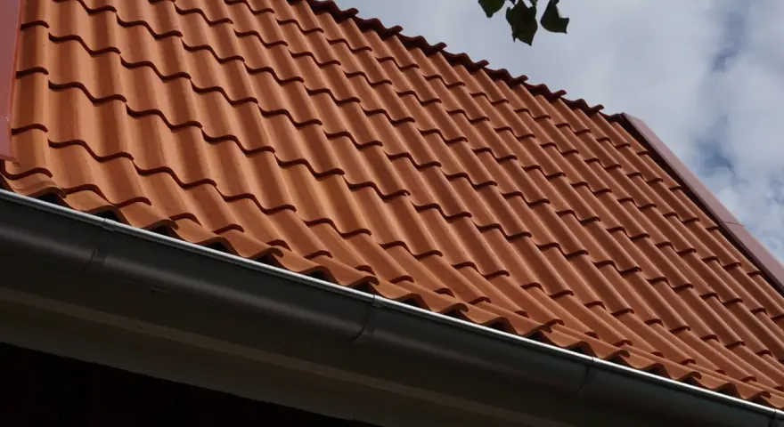 Rött tegeltak med rännsten. Taket har en minimal taklutning för betongpannor, vilket ger ett stilrent utseende.
