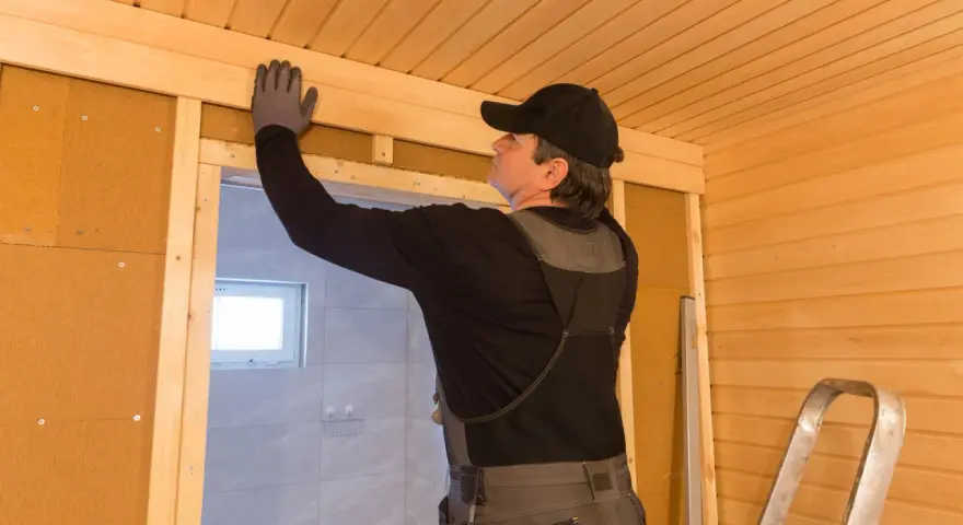 Man bygger bastu inomhus, monterar träpanel i taket.
