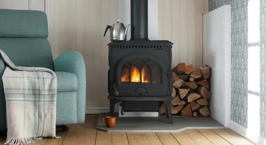 Mysig brasa i gjutjärnskamin med ved och tekopp. Tänk på renovera skorsten pris för en säker och effektiv värme.