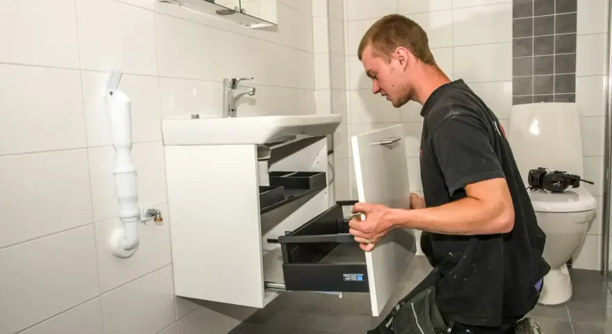 Hantverkare installerar ett nytt badrumsskåp under en totalrenovering av badrum.