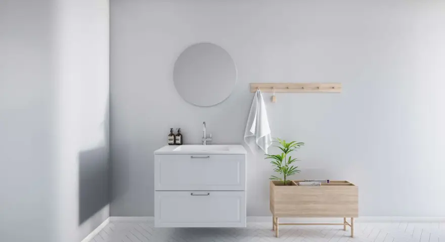 Minimalistiskt badrum med vitt kommod, rund spegel och trädetaljer. En bra utgångspunkt för att fundera på vad kostar det att renovera ett litet badrum.
