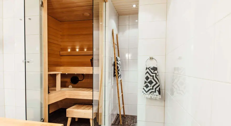 En liten bastu i badrummet, perfekt för avkoppling. Trädetaljer och en duschhörna skapar en spa-känsla.