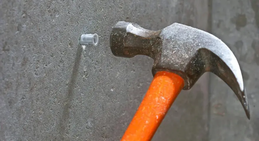 Hammare slår in en plugg i betongvägg. Förberedelse för att skruva i betong.