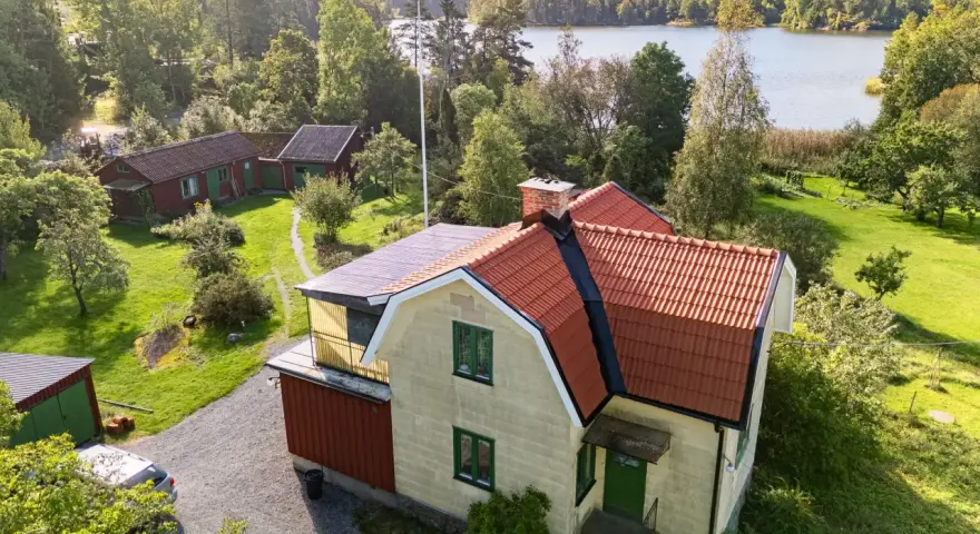 Gult hus med tegeltak vid en sjö. En takrenovering kostnad kan vara en bra investering för att skydda huset.
