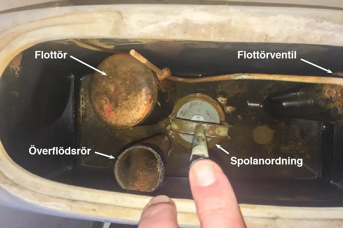 Insidan av en cistern där flottören och spolmekanismen syns. Vattennivån är låg, vilket kan tyda på att toaletten rinner efter spolning.